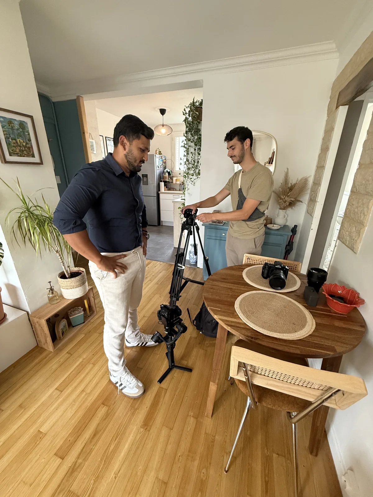 Shawez Ali, en chemise bleue, et le vidéaste installent le trépied et le stabilisateur dans un appartement lumineux