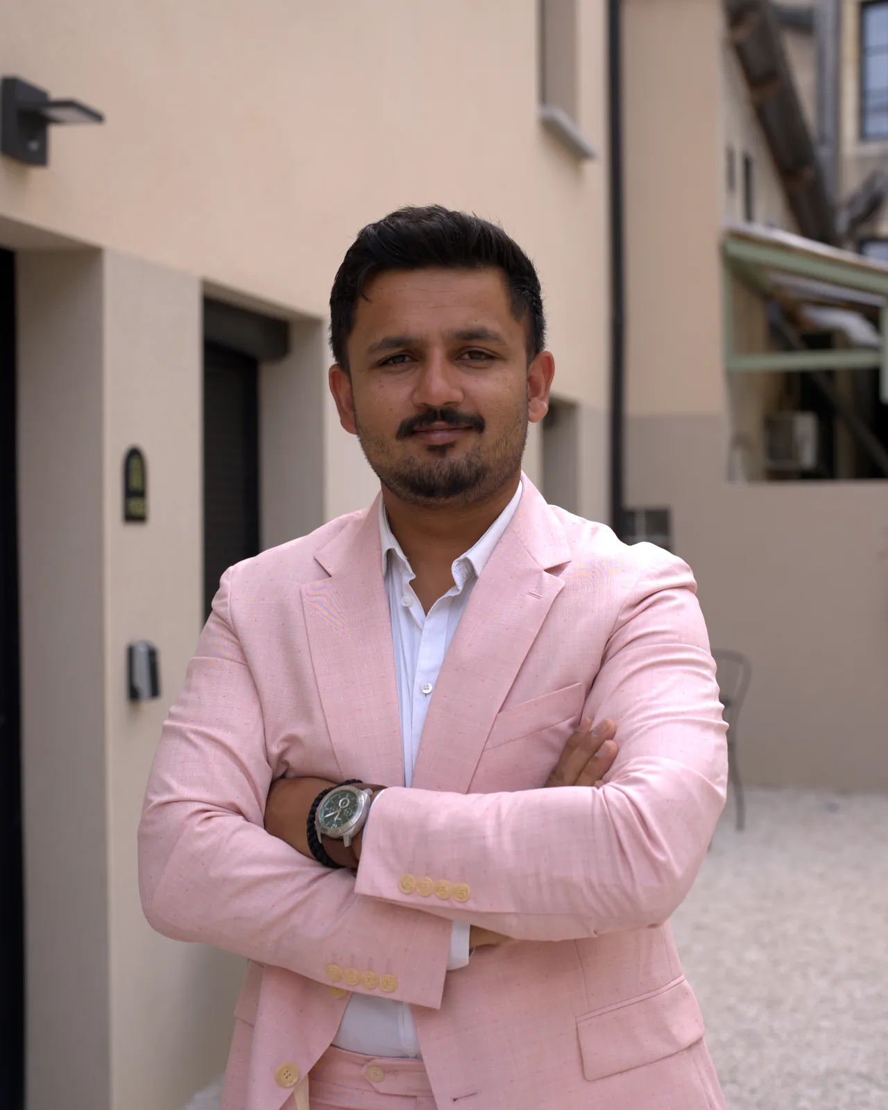 Portrait de Shawez Ali, agent immobilier à Dijon, en costume rose, bras croisés